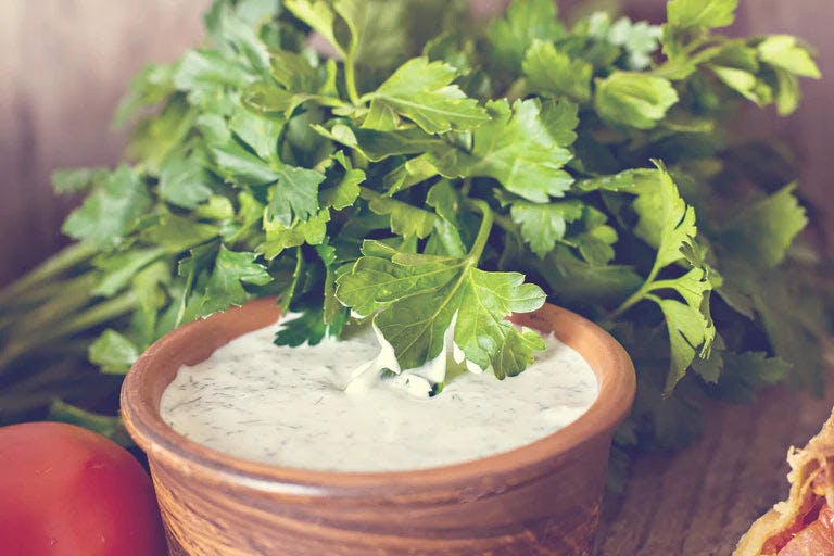 Fresh bowl of zesty yogurt veggie dip topped with herbs