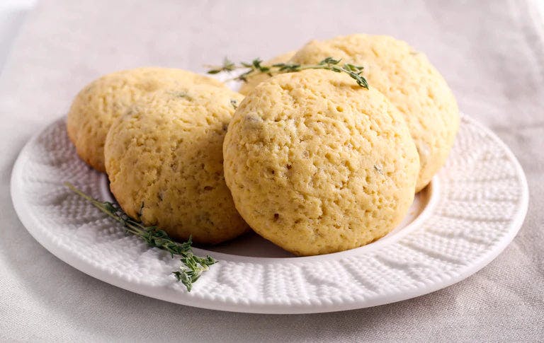 Four cookies garnished with thyme on white plate