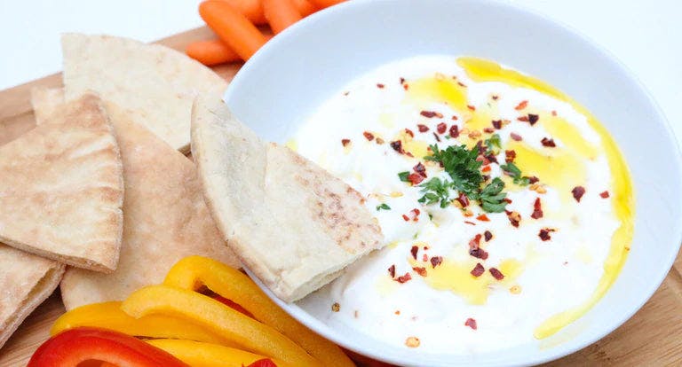 Bowl of feta dip garnished with red pepper flakes and pita chips