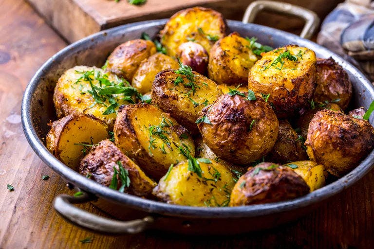 Roasted potatoes in pan with herbs sprinkled on top