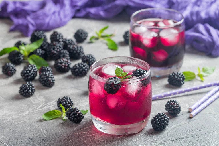 A delicious magenta blackberry gin and tonic with blueberries on the side.