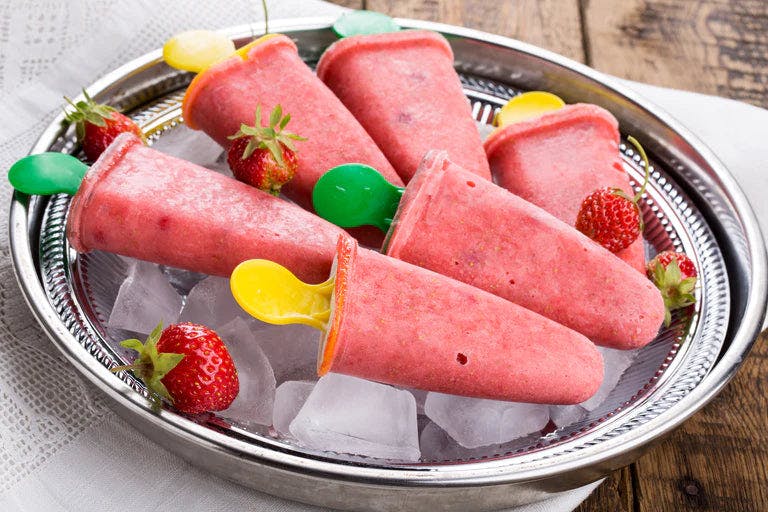 Delicious strawberry mango popsicles on a wooden table