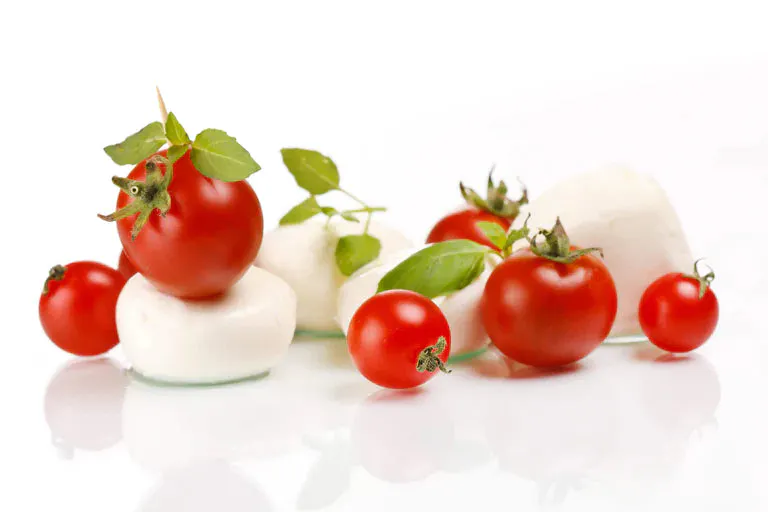 Fresh mozzarella and basil stuffed tomatoes on a plate.