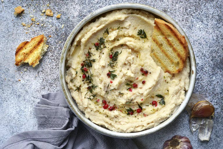 A bowl of lemon herb hummus on a table