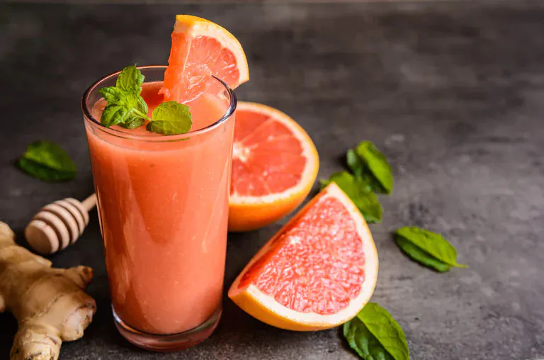 Ruby red chiller in a glass next to a couple grapefruit slices.