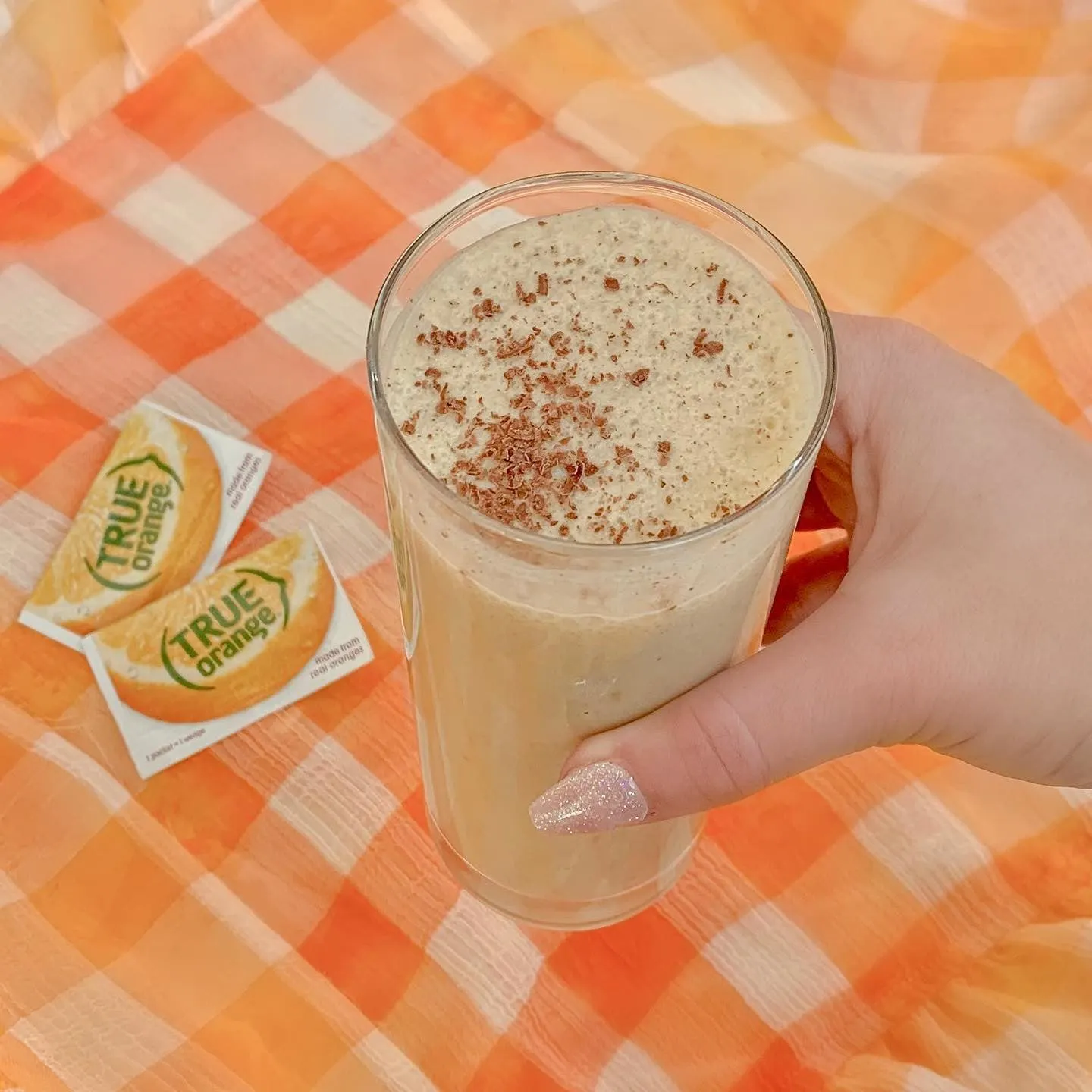 Thick orange smoothie beside 2 packets of True Orange