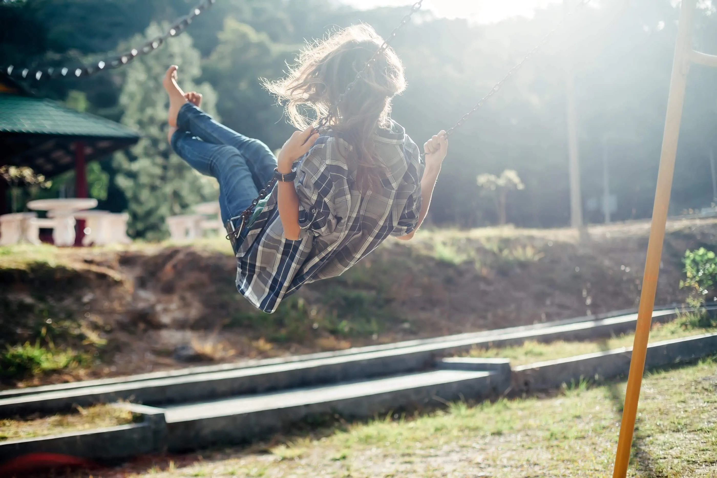 A woman on a swing in the summer sun.