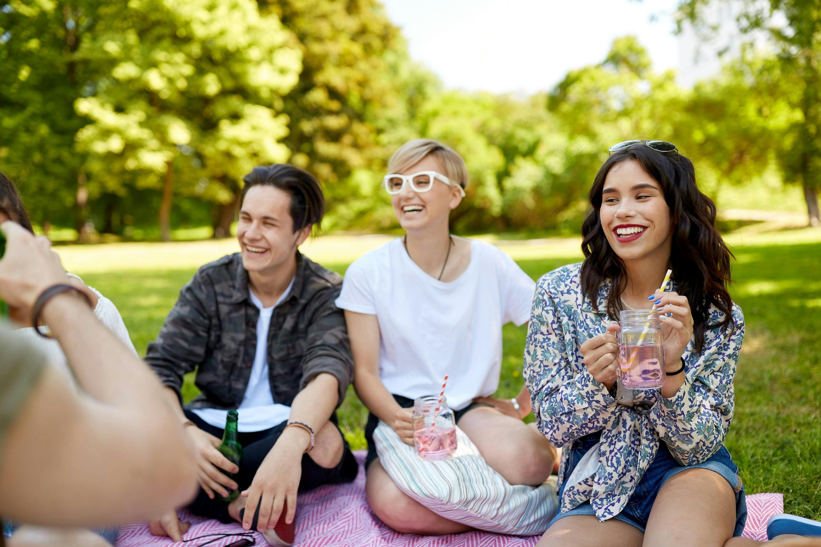 three friends sitting and smiling while drinking beverages