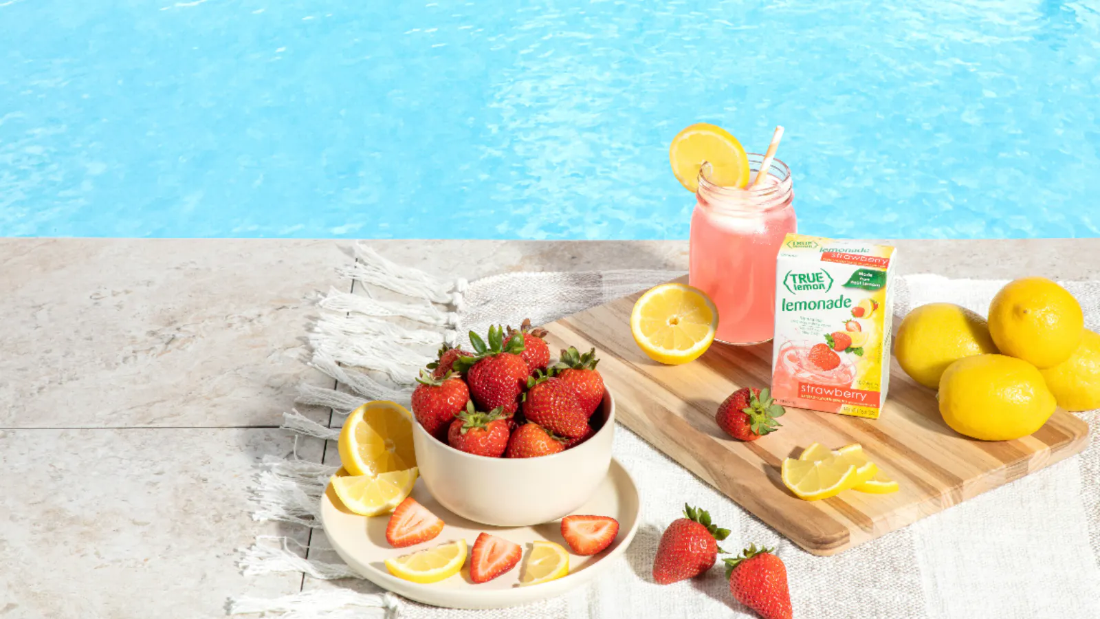 A box of True Lemon Strawberry Lemonade next to sliced open lemons.