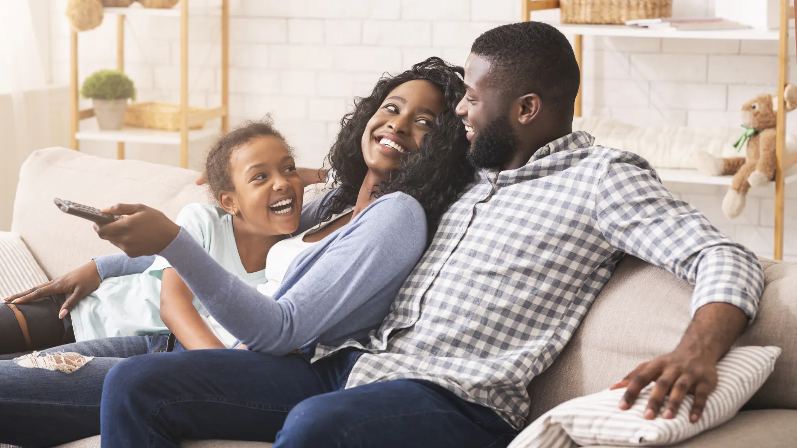 A mom, dad, and daughter sitting on a couch together smiling.