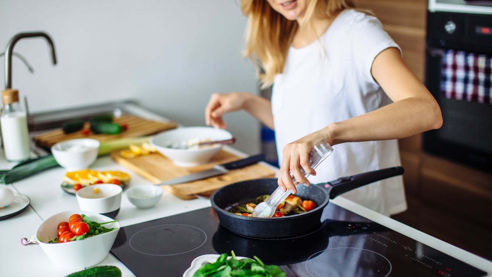 Woman cooking several dishes over an open stovetop