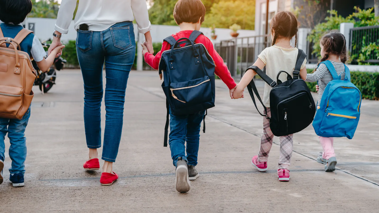 A mother and her four kids who are back-to-school ready. All the kids are wearing backpacks that are too big for them.
