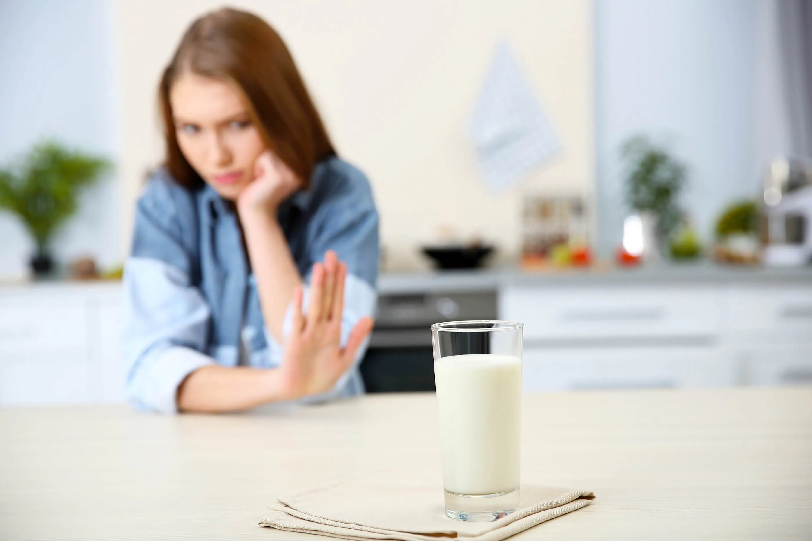 woman putting up hand to say no to glass of milk