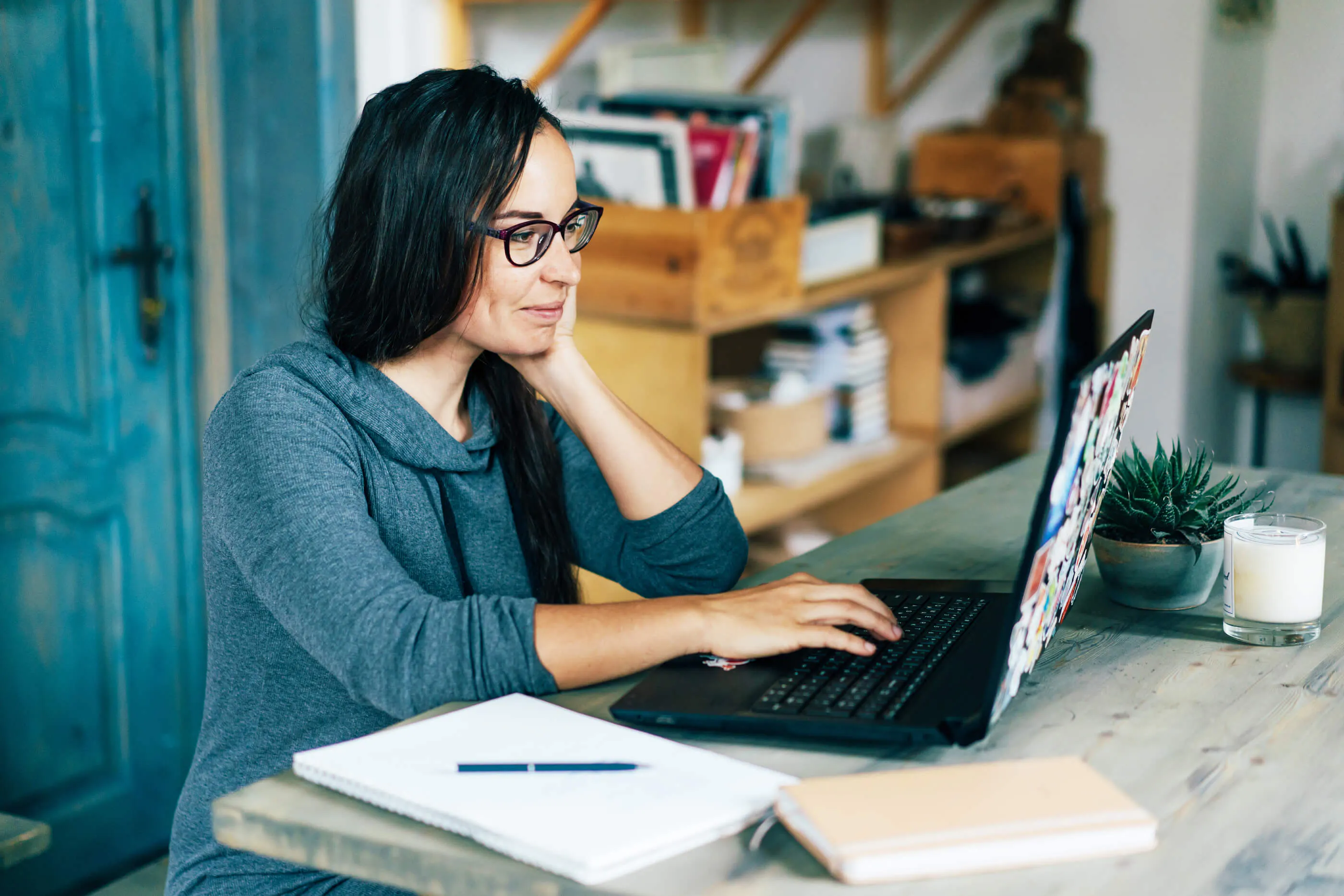 A woman is sitting at a desk looking at her computer.