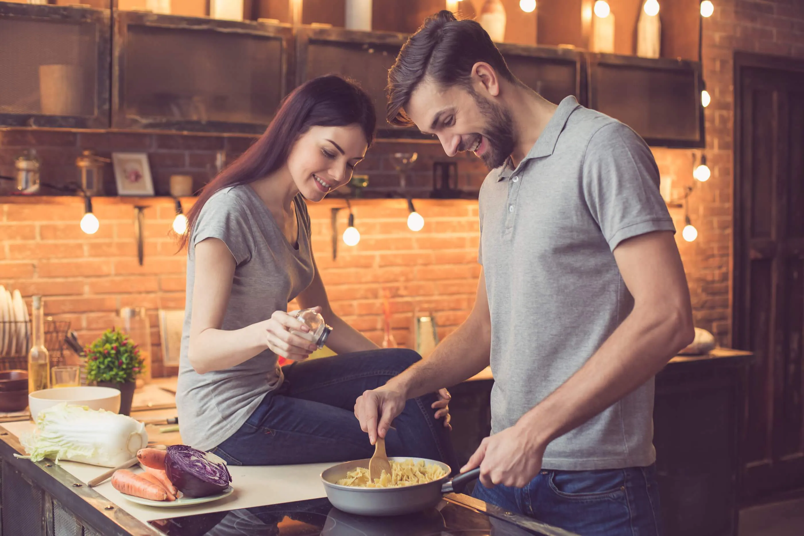 A man and a woman in a kitchen cooking together.