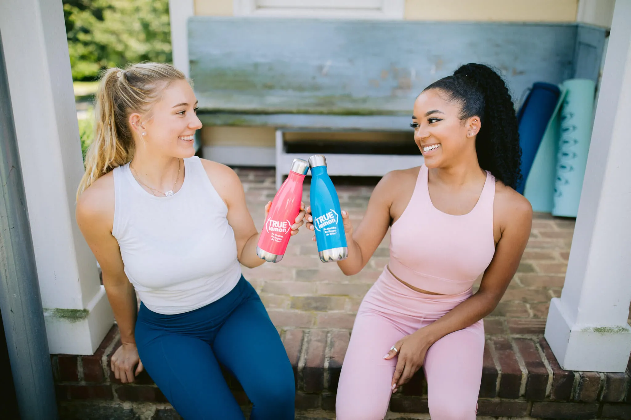 two women tapping metal water bottles together