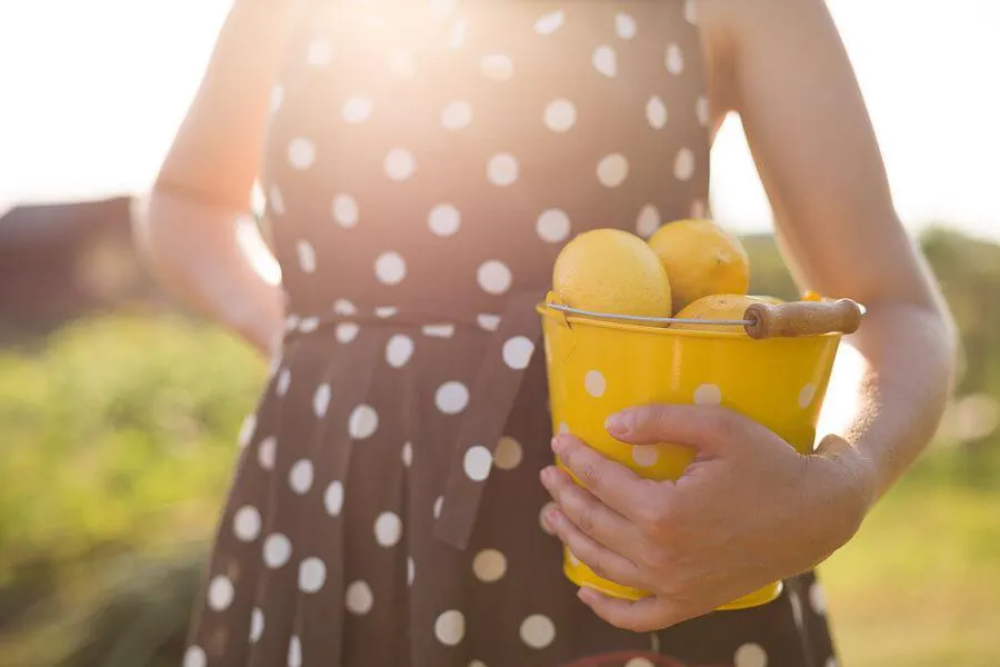 woman holds bucket of lemons