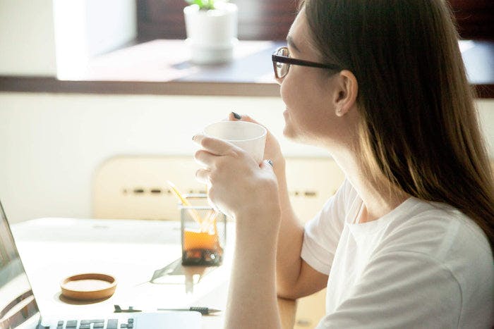 women sips from a coffee cup with looking out the window