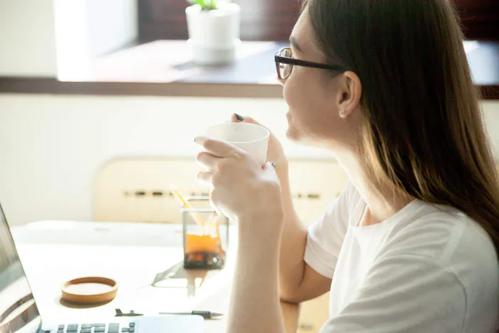 women sips from a coffee cup with looking out the window