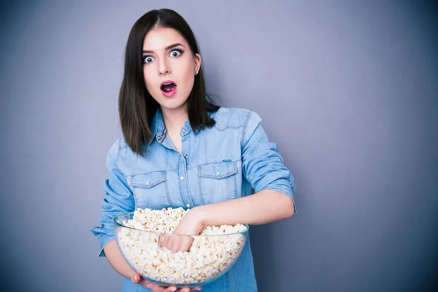 woman eating popcorn out of a giant glass bowl