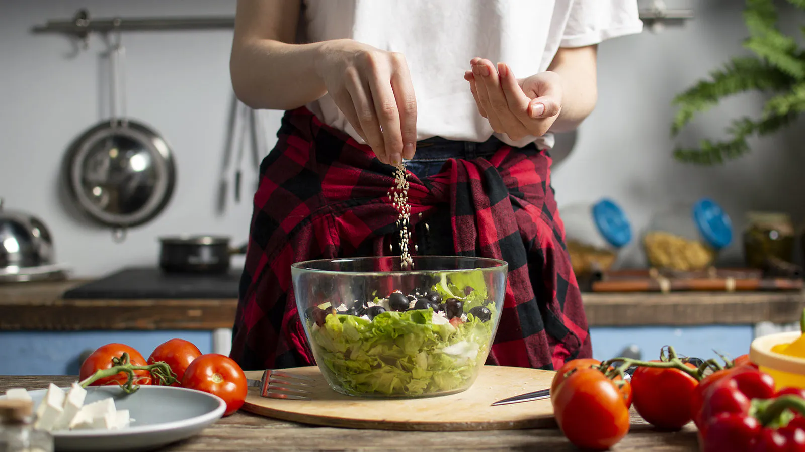 woman adding sesame seeds to salad