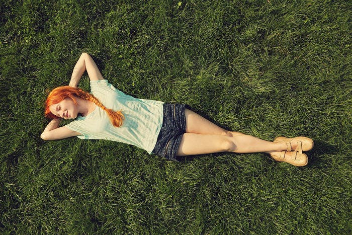 women lays in the grass with her hands behind her head