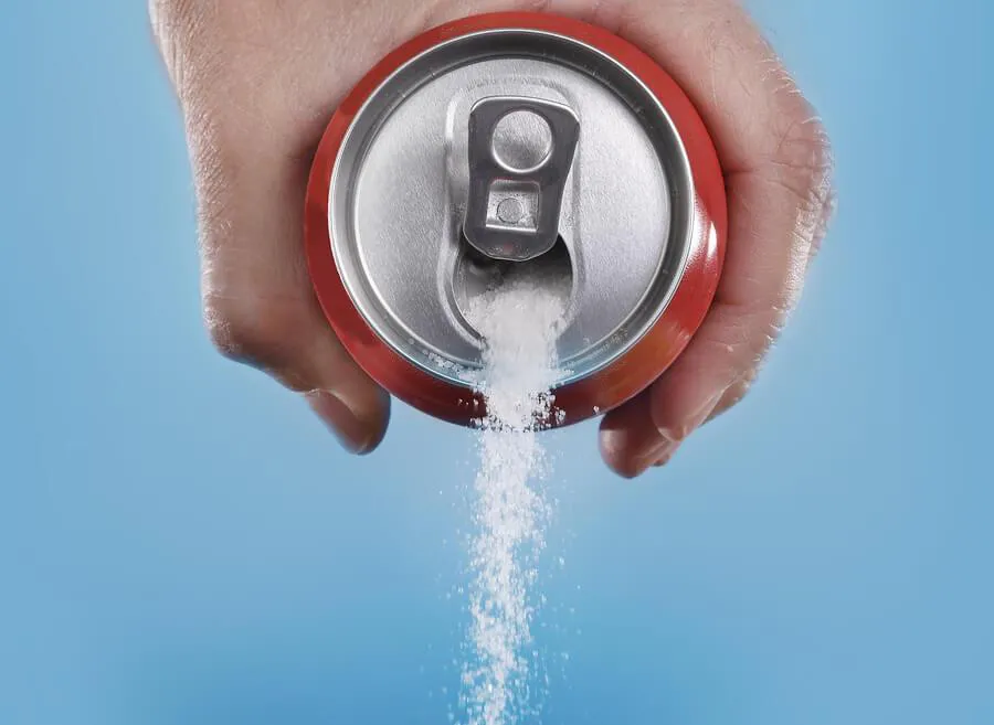 a man pouring a can of soda that is filled with sugar