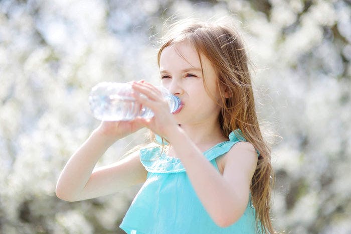 little girl drinks from a water bottle