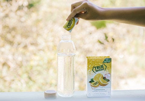 True Lemon product poured into glass water bottle outside